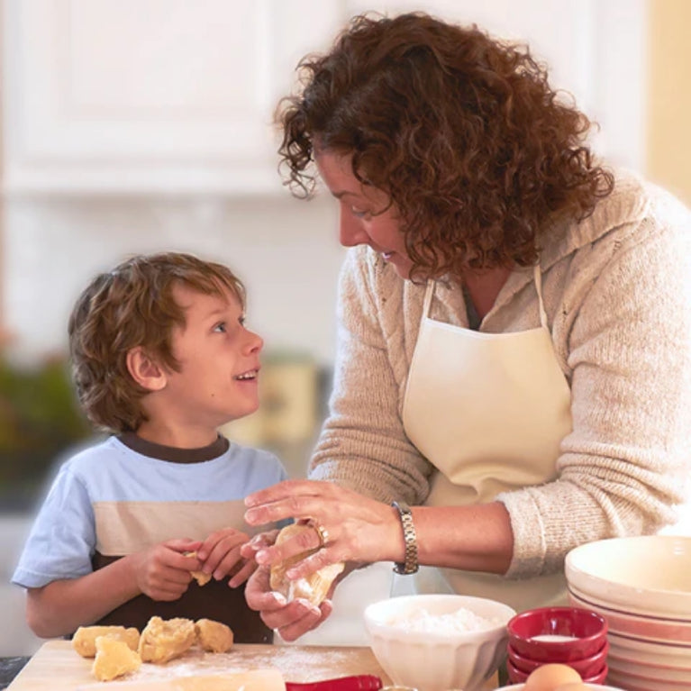 Woman speaking to smiling boy while they make dough