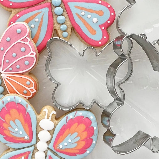Butterfly cookie cutters and cookies on a white plate