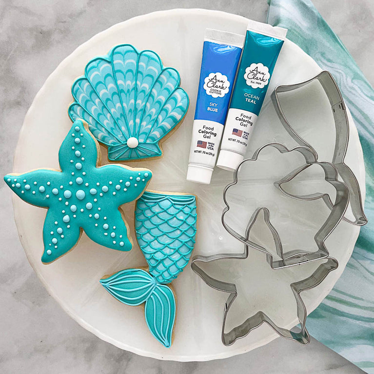 Mermaid cookies with cookie cutter shapes and food coloring on a plate